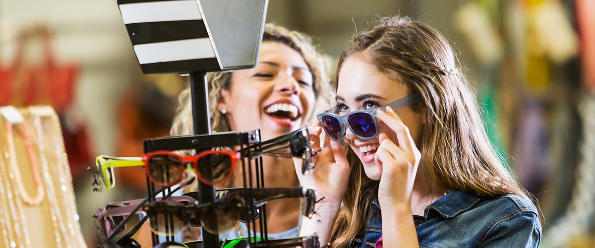 Fidelice a sus clientes - dos jóvenes se prueban gafas en una tienda Fidelice a sus clientes - dos jóvenes se prueban gafas en una tienda