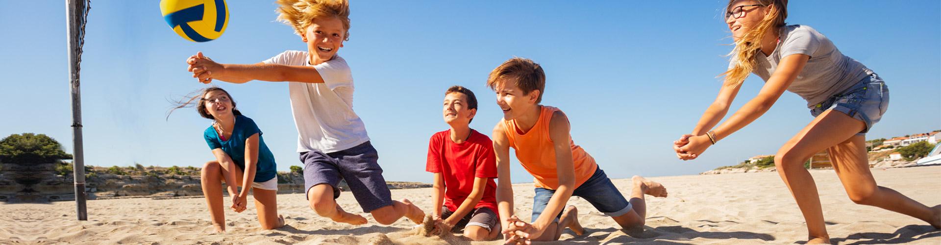 niños jugando al voleibol en la playa